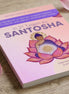 Das Buch "Santosha" in lila-rosanem Cover mit meditierendem Buddha in einem großen roten Lotus, vor dessen Herz eine Sonne erstrahlt.